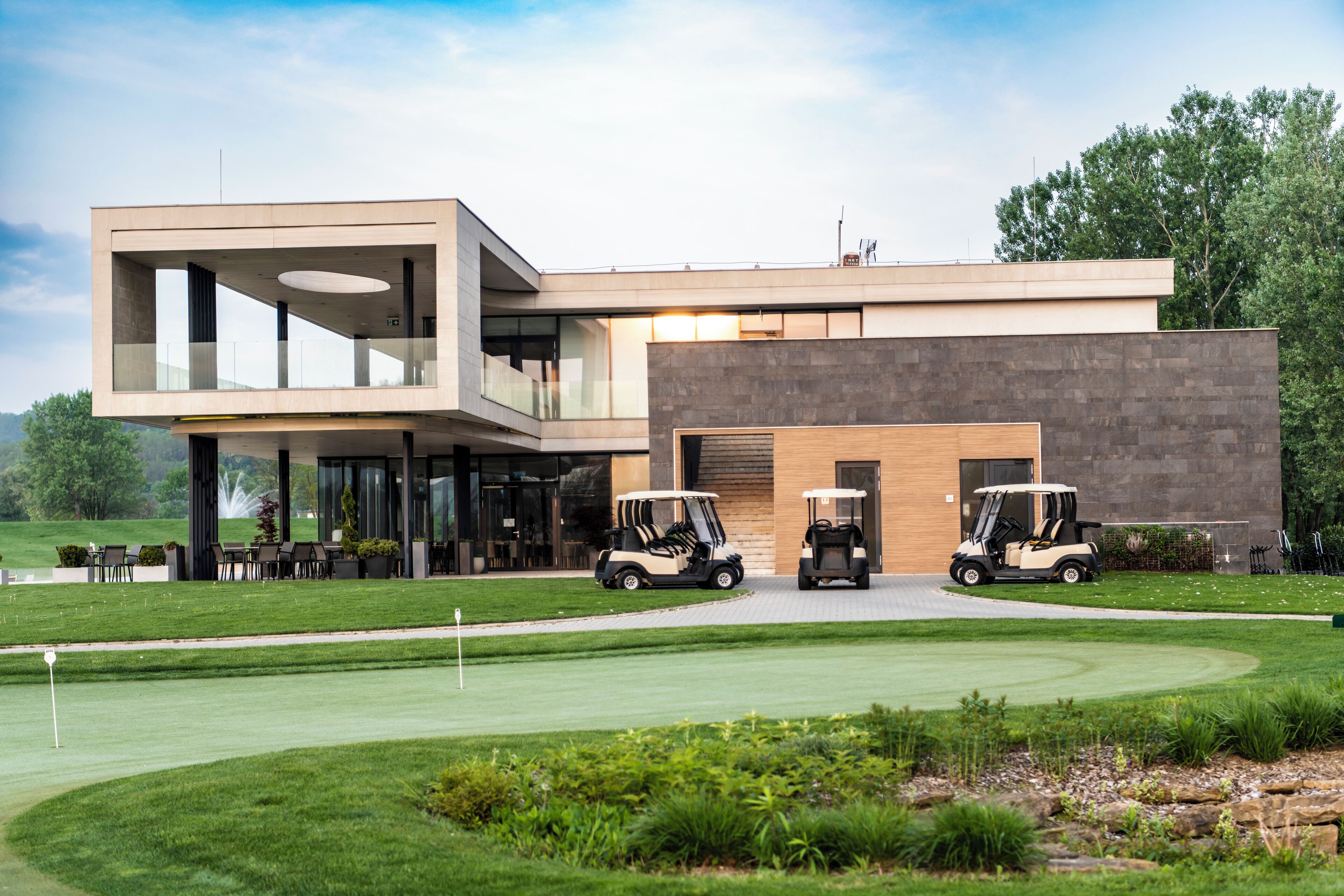 A modern building with a flat roof, large windows, and a golf cart in front.