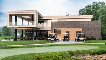 A modern building with a flat roof, large windows, and a golf cart in front.