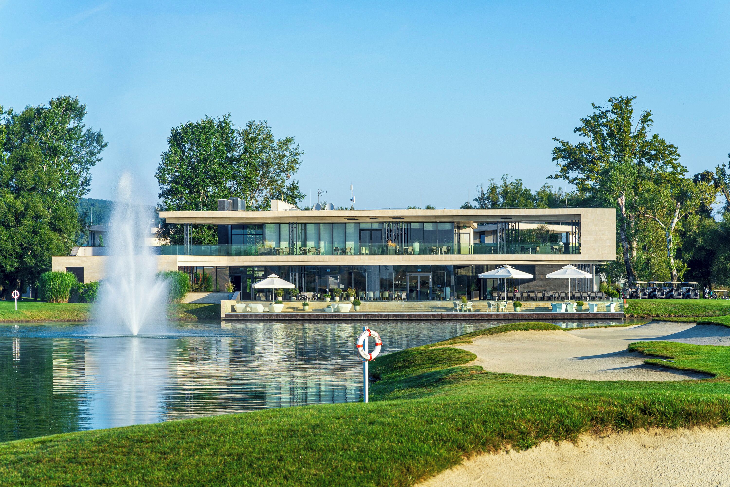 A modern building with a pool, fountain, and outdoor seating area.