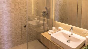 A modern bathroom with a glass-enclosed shower, a large sink, and a mirror.