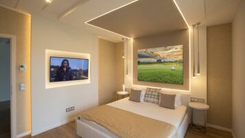 A modern bedroom with a large bed, a flat-screen TV mounted on the wall, and a painting of a golf course.