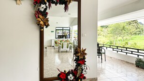 A hotel lobby with a large mirror reflecting a Christmas decoration, a reception area, and a view of a green landscape. - Hotel Tierra Maravilla (Salento)
