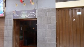 Un edificio con un letrero que dice 'Posada Inka Mango Papac' y un portón metálico cerrado.