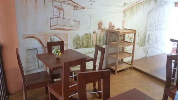 Un comedor con un mural de un paisaje urbano, muebles de madera y una pequeña mesa con un jarrón de flores.