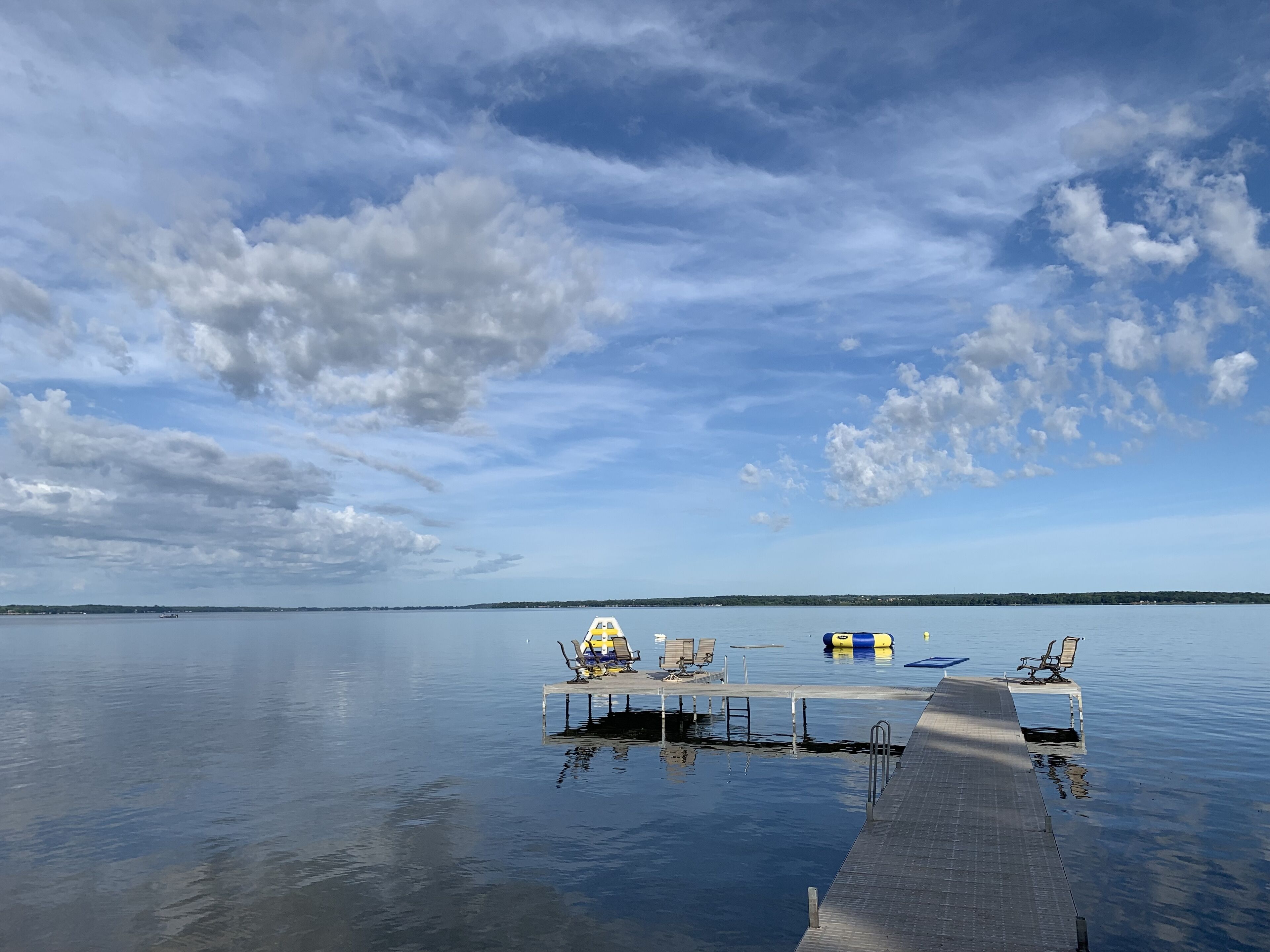A pier extending into calm water with a clear sky above.