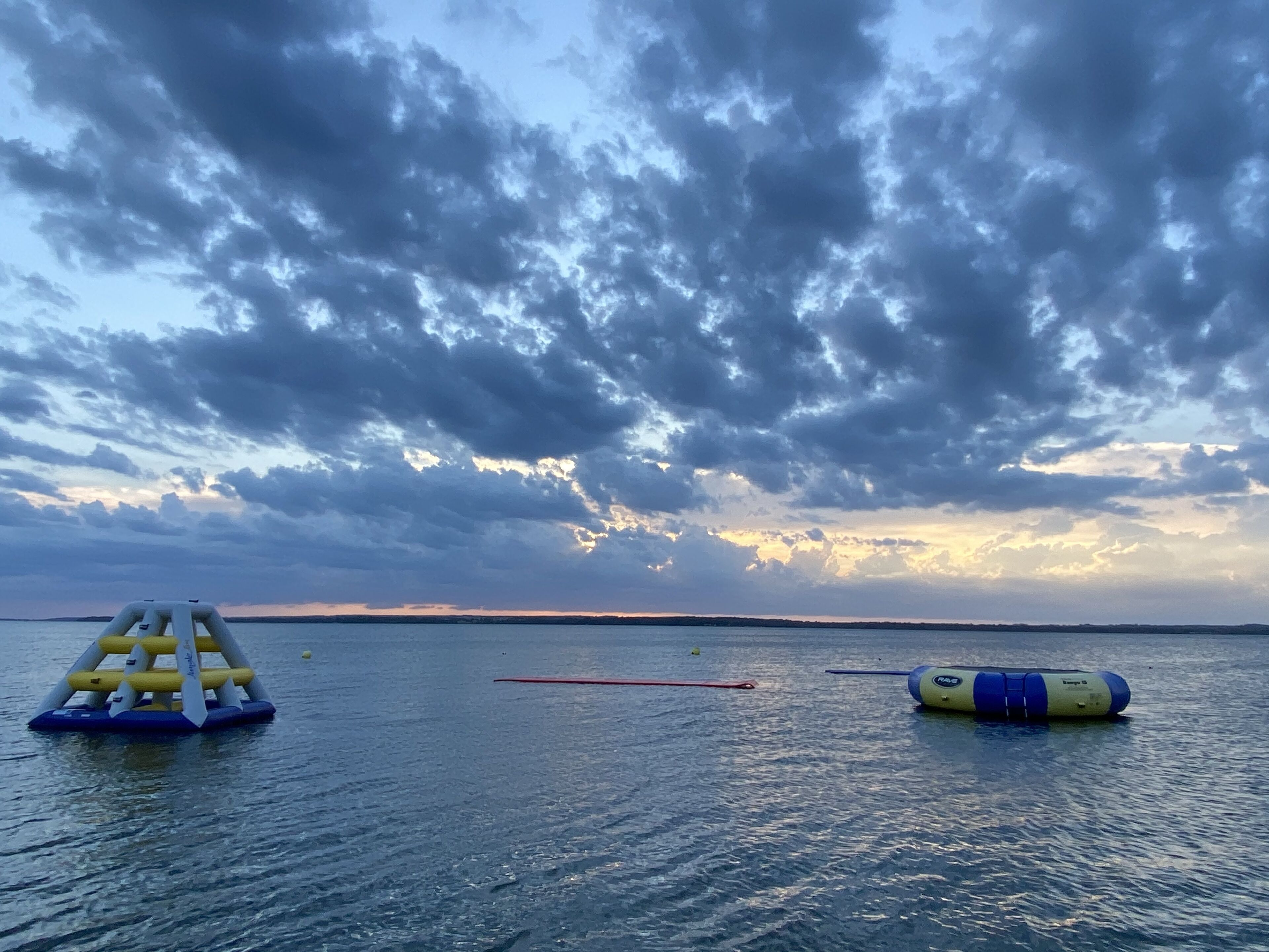 A calm body of water with inflatable structures and a cloudy sky.