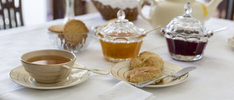 Una mesa dispuesta con una taza de té, galletas y dos recipientes de mermelada.