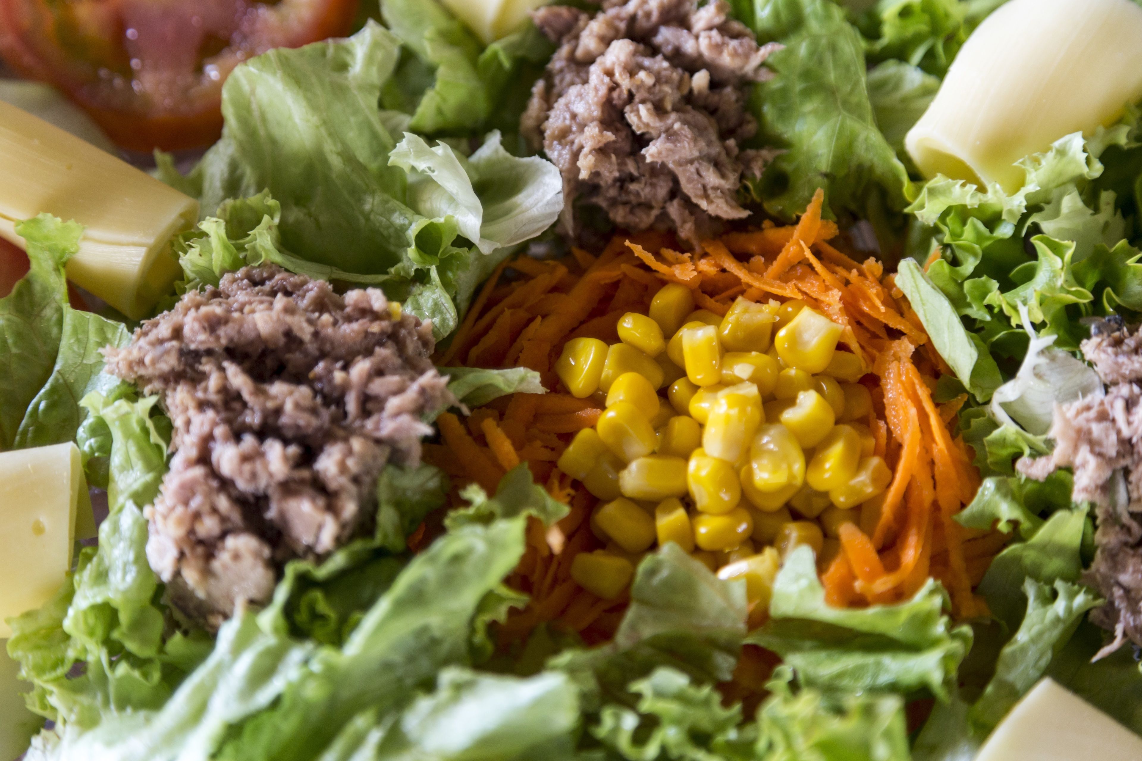 A salad with lettuce, meat, corn, and carrots.