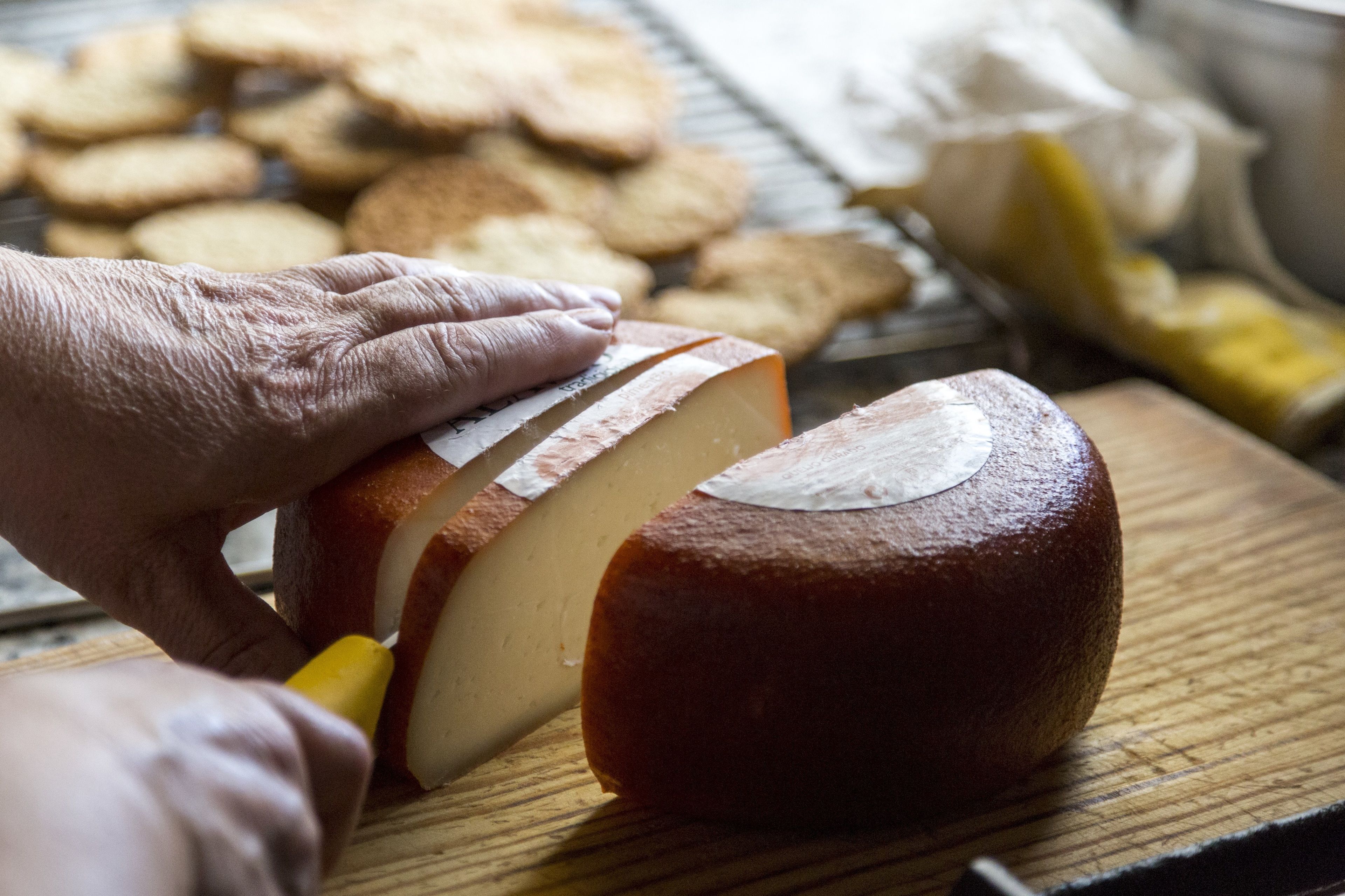 A loaf of bread being sliced on a wooden cutting board.