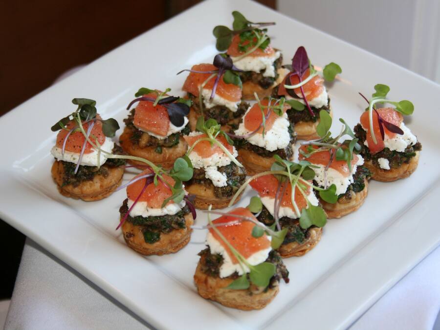 A white rectangular plate with several appetizers arranged in a grid pattern.