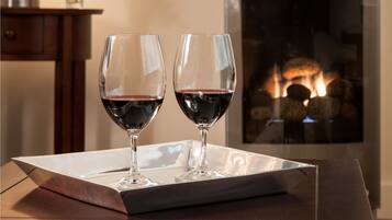 A table with two wine glasses and a tray, a lamp, and a fireplace in the background.