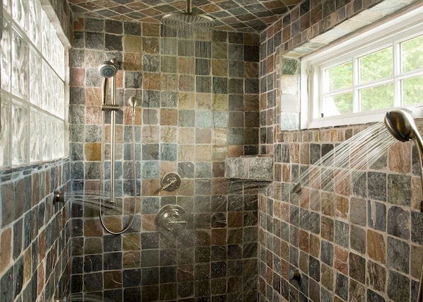 A shower with a stone mosaic wall, a window, and a showerhead. - Sugar Hill Inn (Sugar Hill)