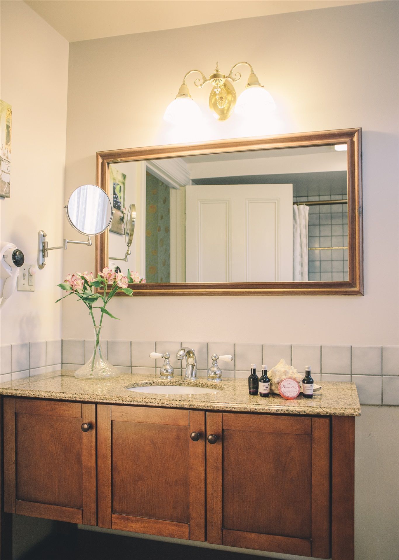 Un baño con tocador de madera, un espejo grande y un aplique de pared.