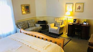 A hotel room with a bed, a sofa, a chair, a desk, and a lamp.