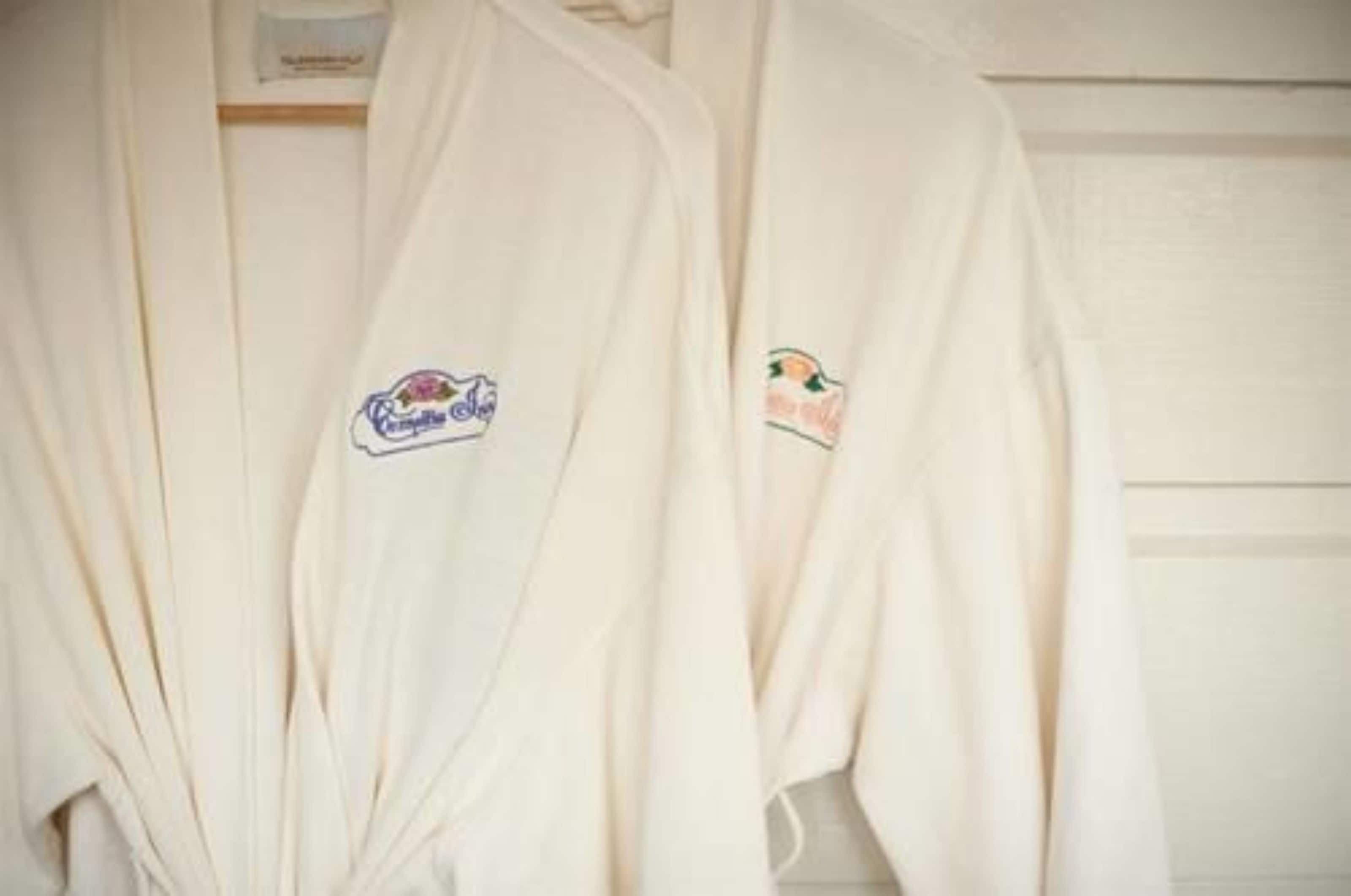 Twee witte gewaden hangen aan een muur.