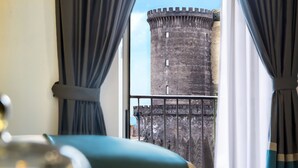 Habitació amb vista a una torre històrica a través d'una finestra amb cortines.