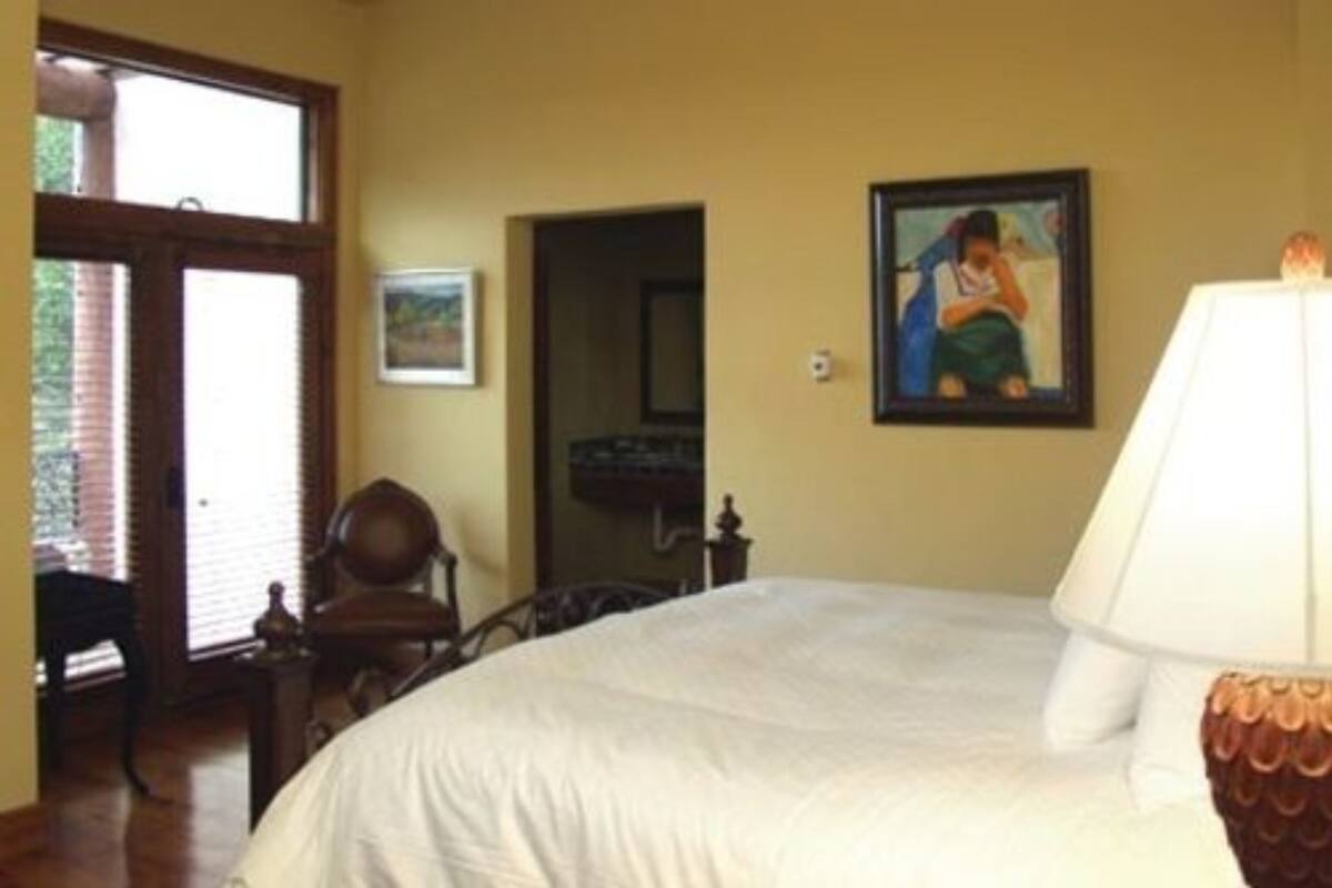 A bedroom with a large bed, a chair, a lamp, and a painting on the wall.