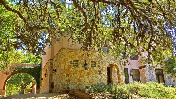 A stone building with an arched entrance, a stone staircase, and a covered walkway.