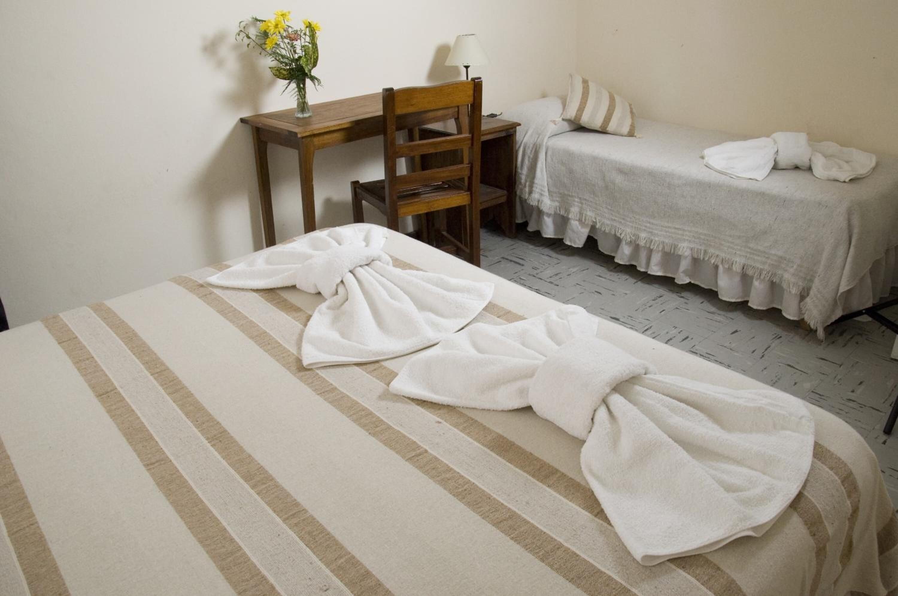 A hotel room with a bed, a chair, a small table with a lamp, and a bedside table with a lamp.