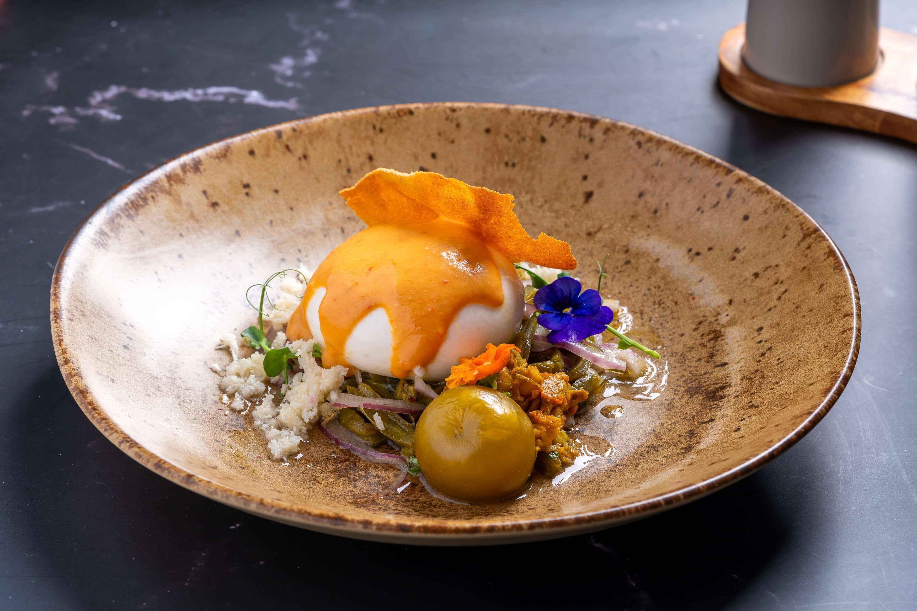 A dessert on a ceramic plate with a flower garnish.