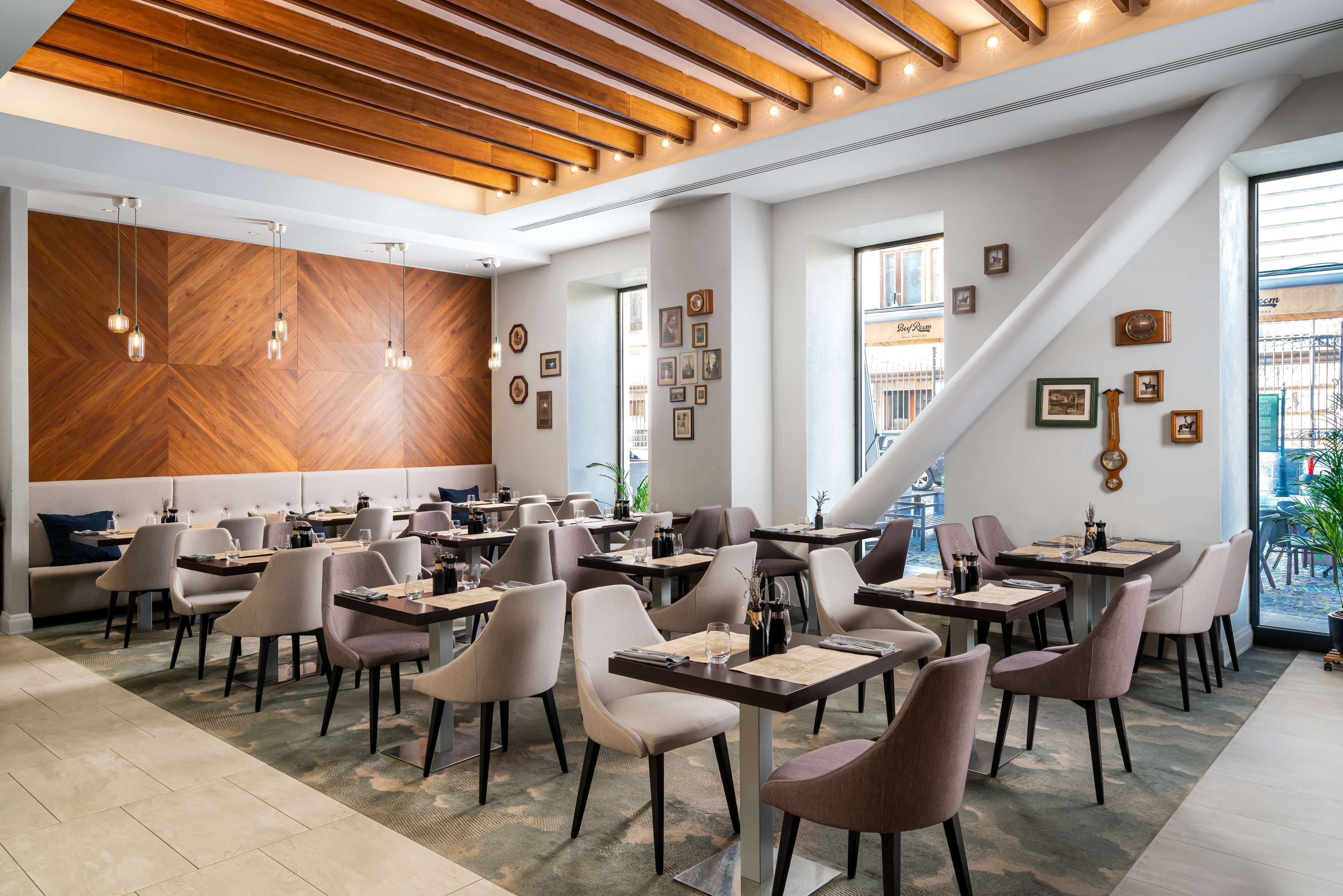 Un restaurante moderno con vigas de madera en el techo, varias mesas y sillas.