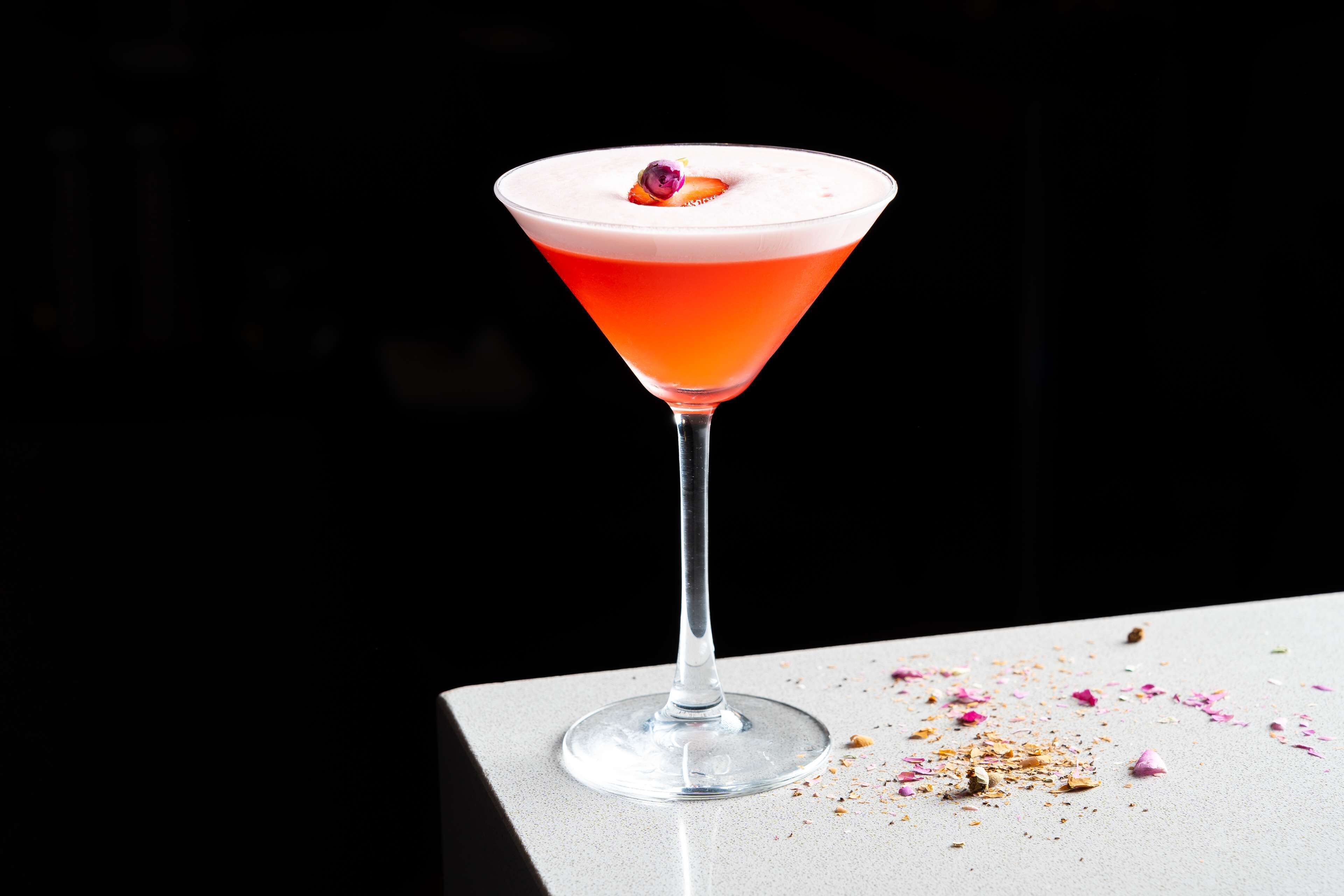 Martini-lasi, jossa on punainen juoma valkoisella alustalla.