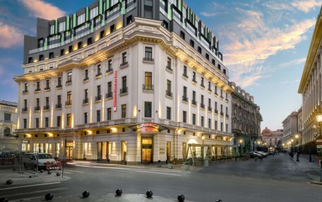 A multi-story hotel with a classic facade, illuminated entrance, and a spacious courtyard.