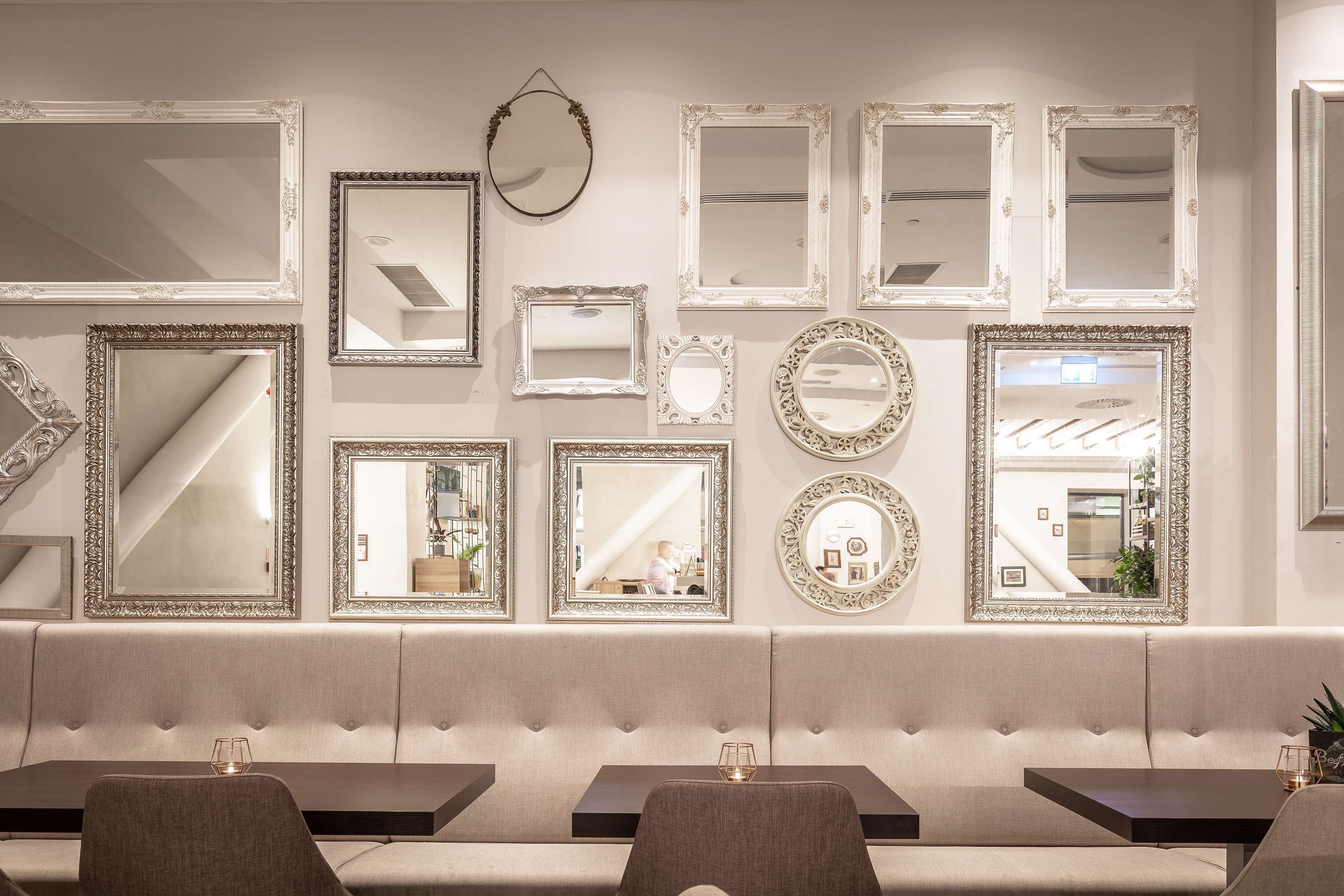 A hotel lobby with a seating area, multiple mirrors, and a staircase in the background.
