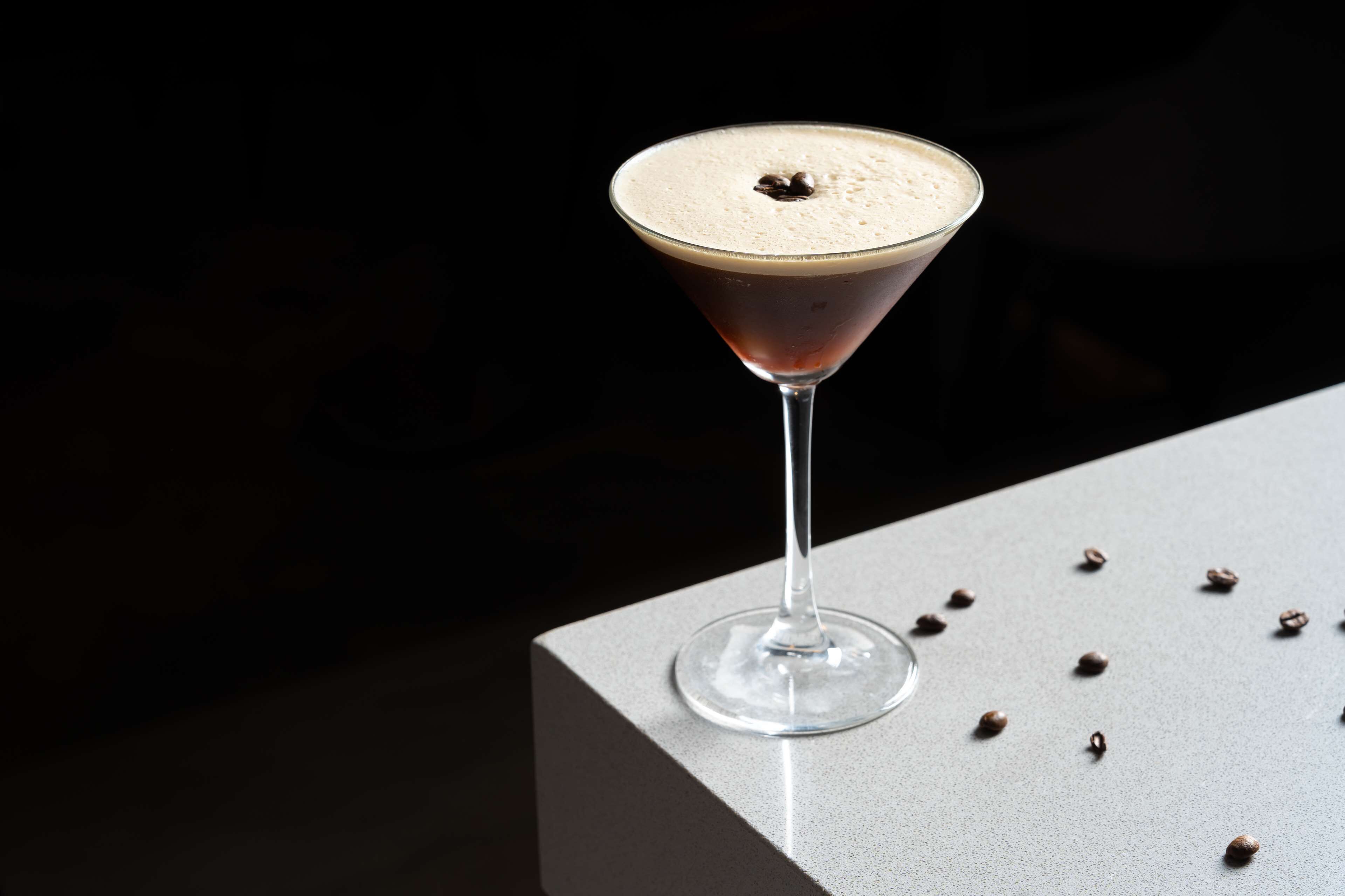 A martini glass with a frothy top on a bar counter.