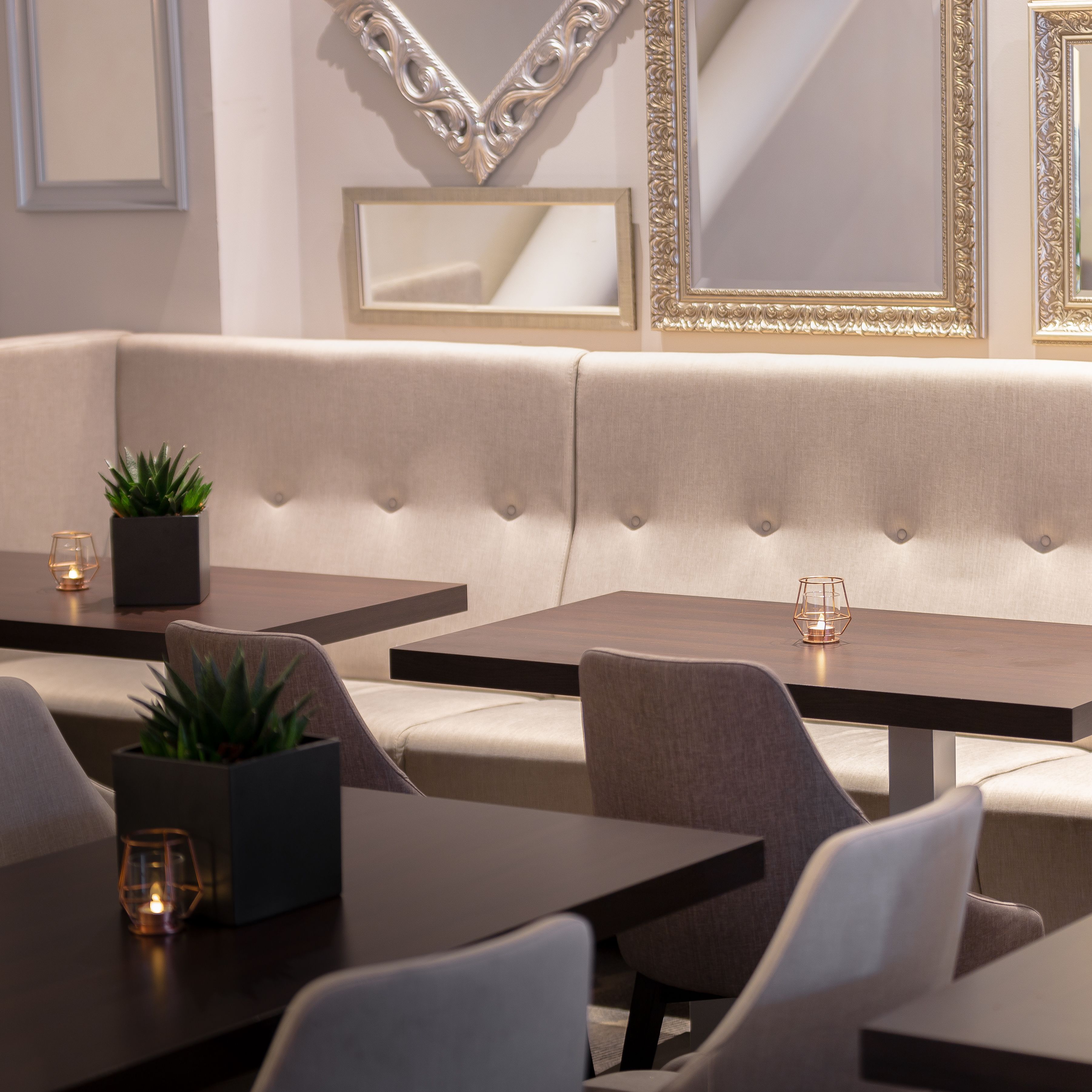 A modern interior with a sofa, tables, and decorative mirrors.