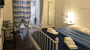 A bedroom with a bed, a desk, a chair, a small table, and a window with curtains. - Amunì - Palermo (Palermo)