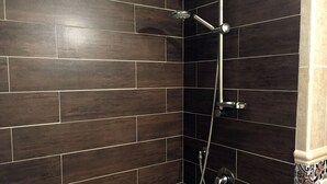 A shower area with dark tiled walls and a chrome showerhead. - Amunì - Palermo (Palermo)
