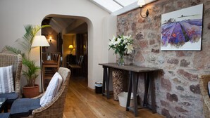 A cozy room with wicker furniture, a stone wall, and a painting.
