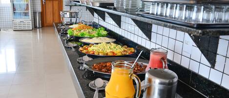 A buffet with various dishes, a juice pitcher, and a coffee pot.