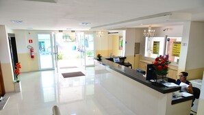 A reception area with a glass door leading outside, a reception desk, and a chandelier. - Sandis Mirante Hotel (Santarém)