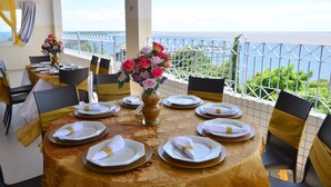 A dining table set for six with a view of the sea, a white railing, and a yellow and gold tablecloth. - Sandis Mirante Hotel (Santarém)