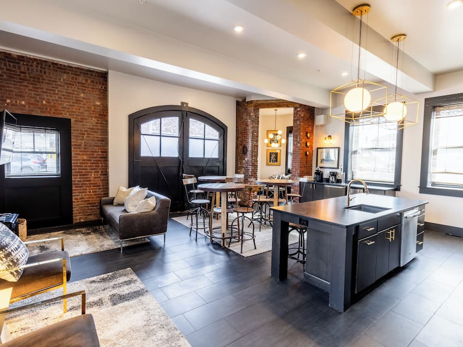 A modern kitchen with a central island, dark cabinetry, and a dining area with a round table and chairs.