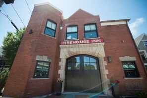 A brick building with a large arched entrance and a sign reading "Firehouse Inn". - The Firehouse (Newport)