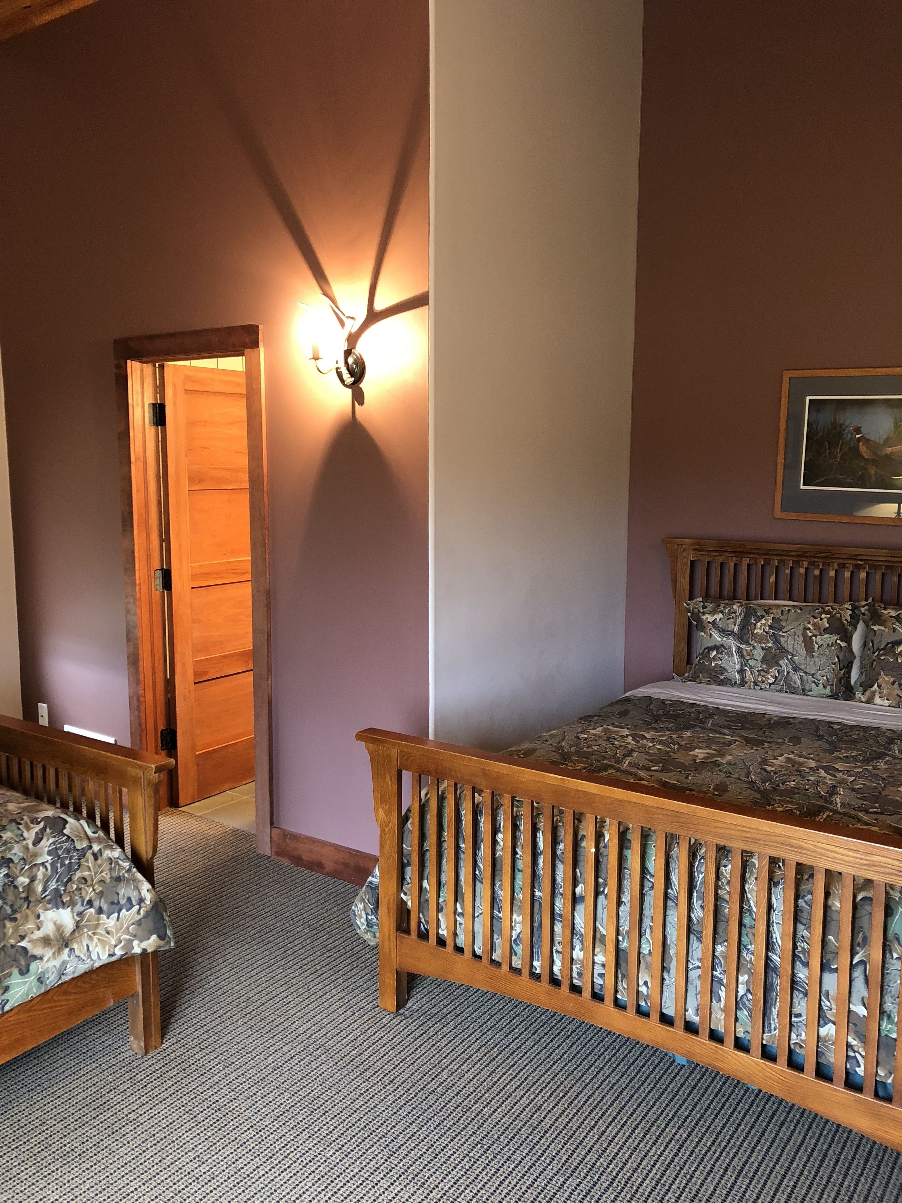 A bedroom with a wooden bed, a nightstand, a chair, and a door leading to another room.