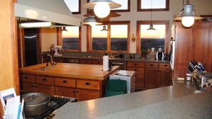 A kitchen with a large island, wooden cabinets, and pendant lighting.