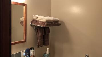 A bathroom with a sink, mirror, towel rack, toilet, and a bottle of liquid soap.