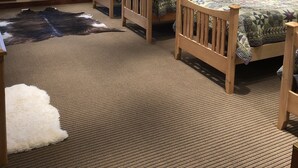 A bedroom with two beds, a large rug, and a fur rug on the floor.