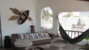 A cozy outdoor seating area with wicker furniture, a hammock, and decorative fish wall art. - Casa Playas 1 (Playas)