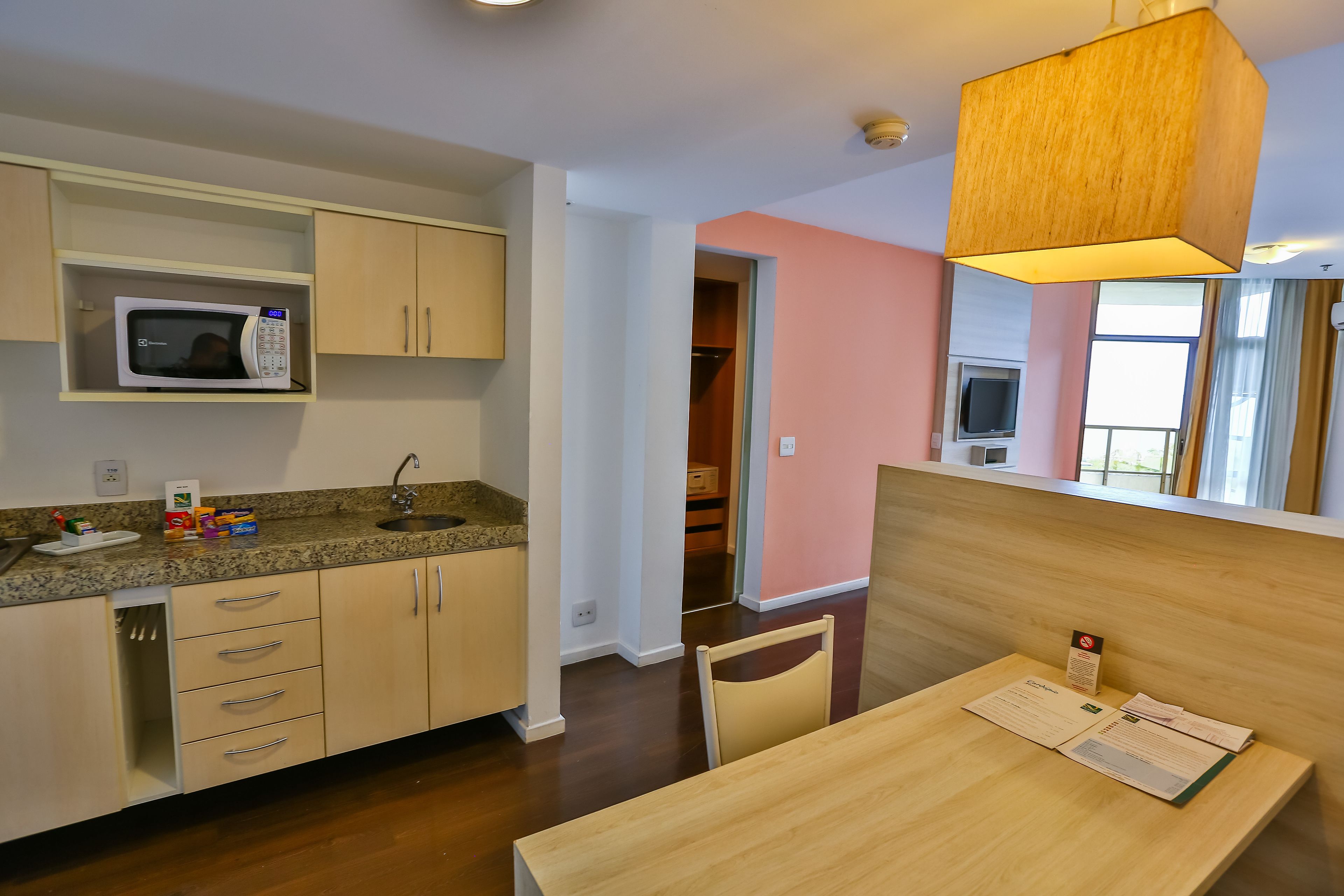 Una cocina moderna con microondas, armarios y un comedor con mesa y silla.