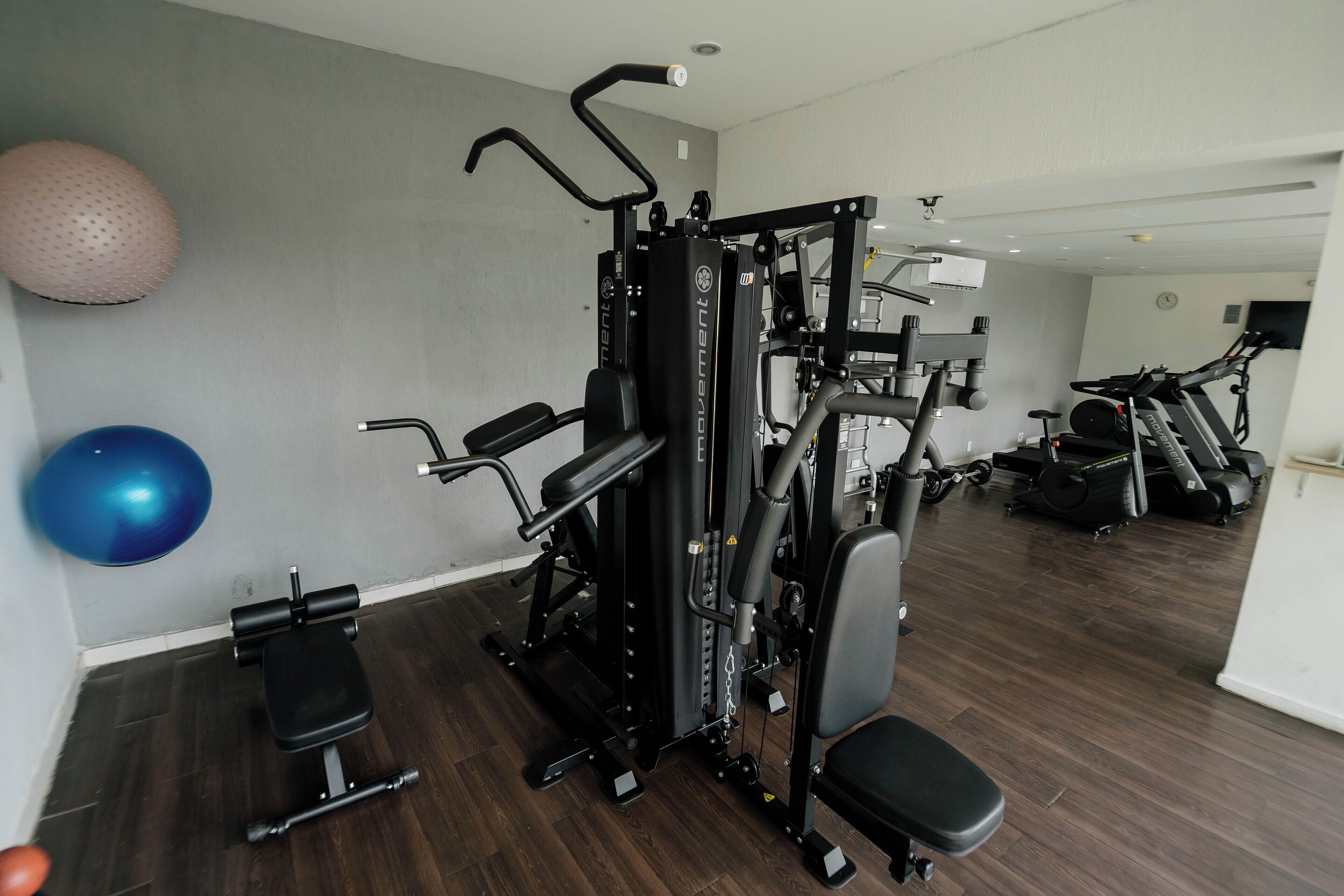 A gym with exercise equipment, a bench, and exercise balls.
