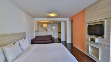 A hotel room with a large bed, a television mounted on the wall, and a sofa in the background.