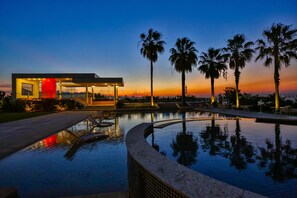 A modern building with a pool, palm trees, and a sunset view. - Hotel Orizzonte Niterói by Atlantica (Niterói)
