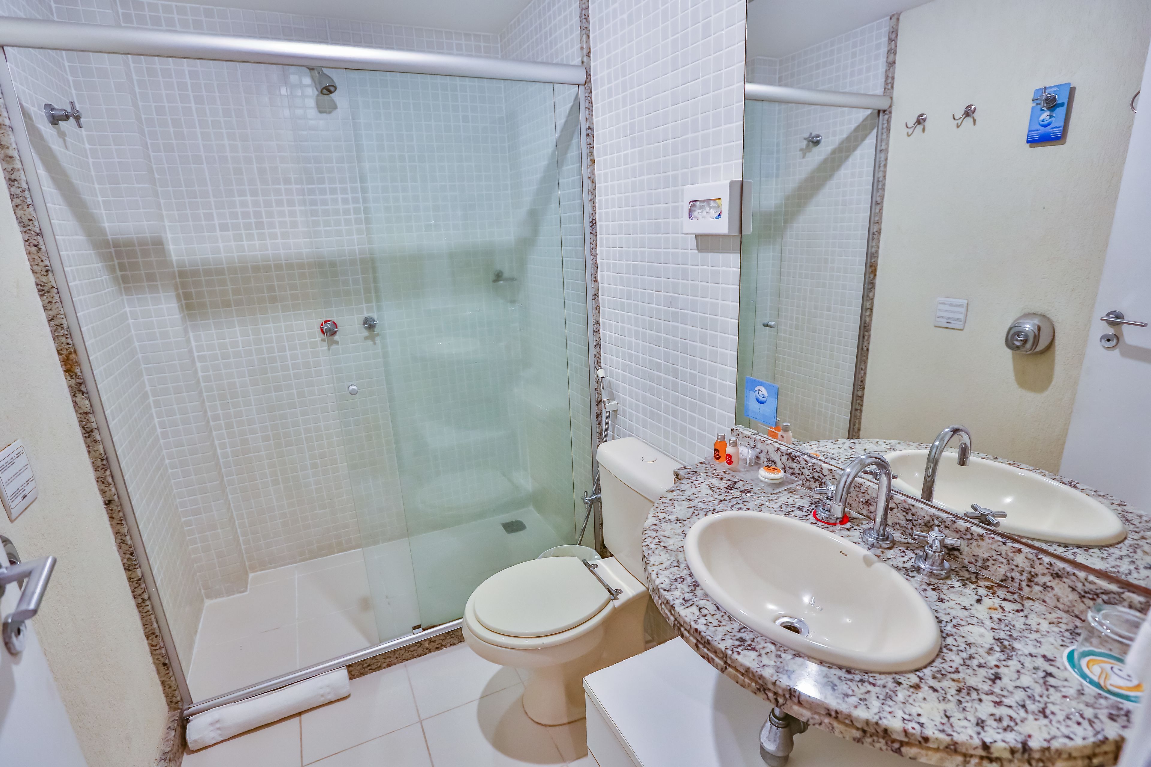 A bathroom with a glass-enclosed shower, a toilet, and a sink with a mirror.