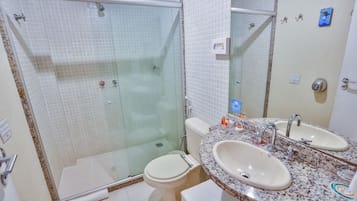 A bathroom with a glass-enclosed shower, a toilet, and a sink with a mirror.