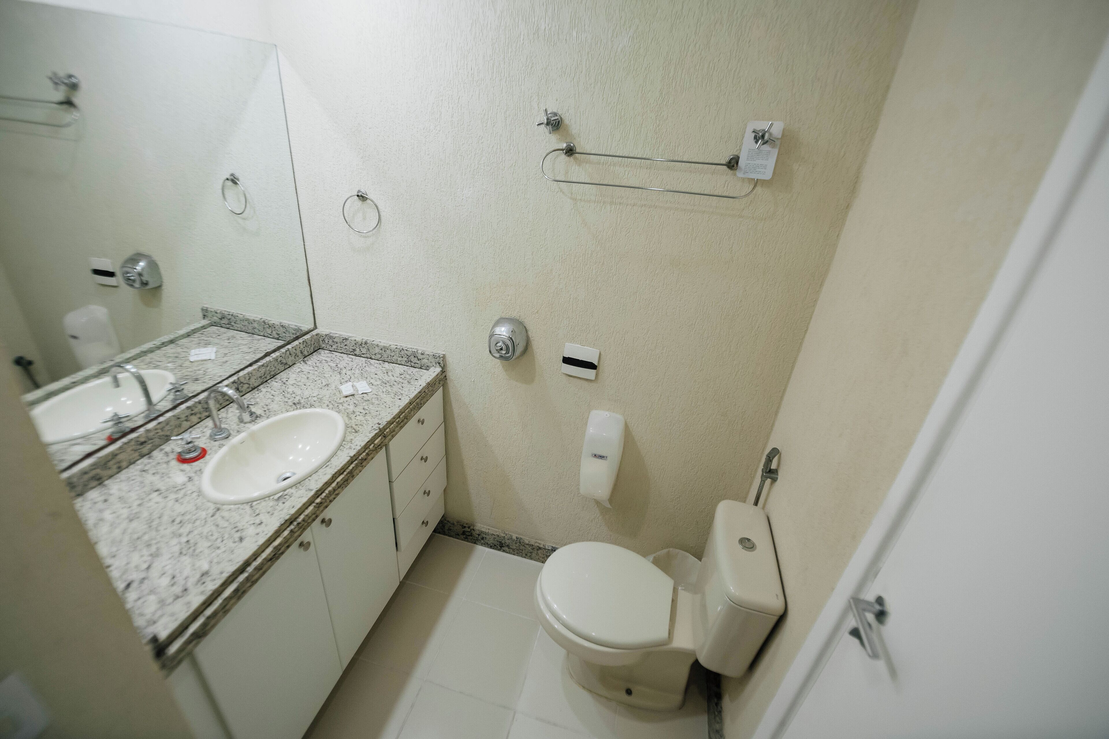 A small bathroom with a sink, mirror, toilet, and towel rack.